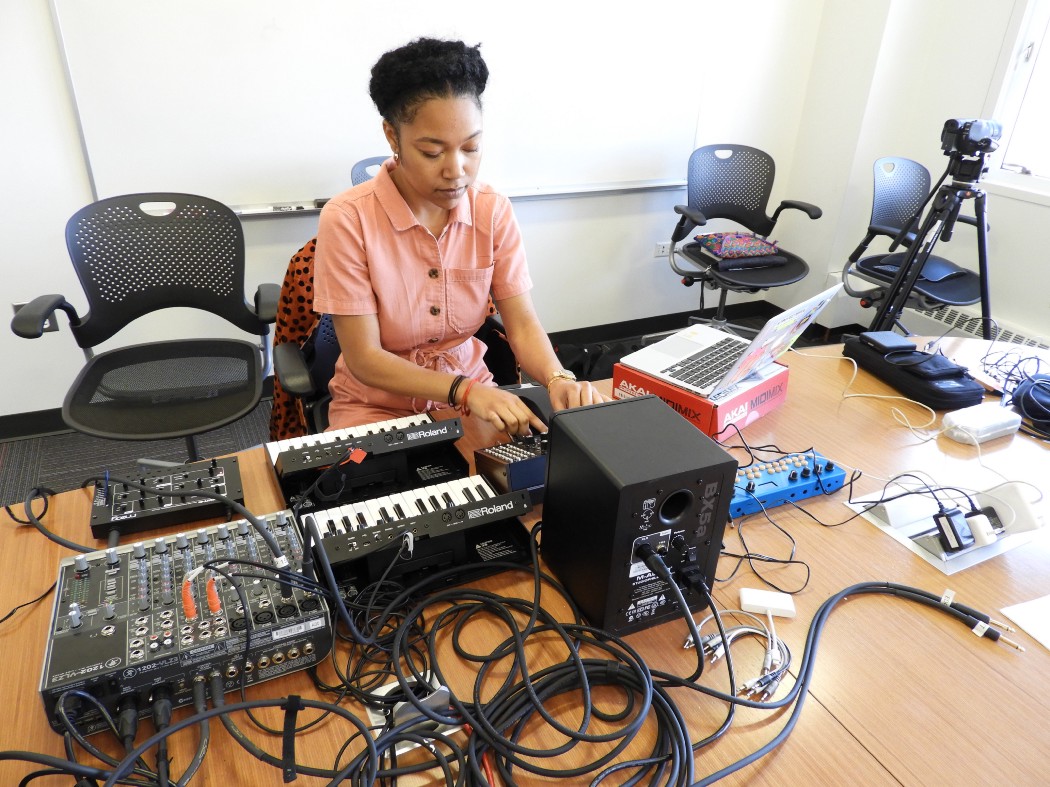 Picture of Ari Melenciano sitting at a table with audio/visual equipment